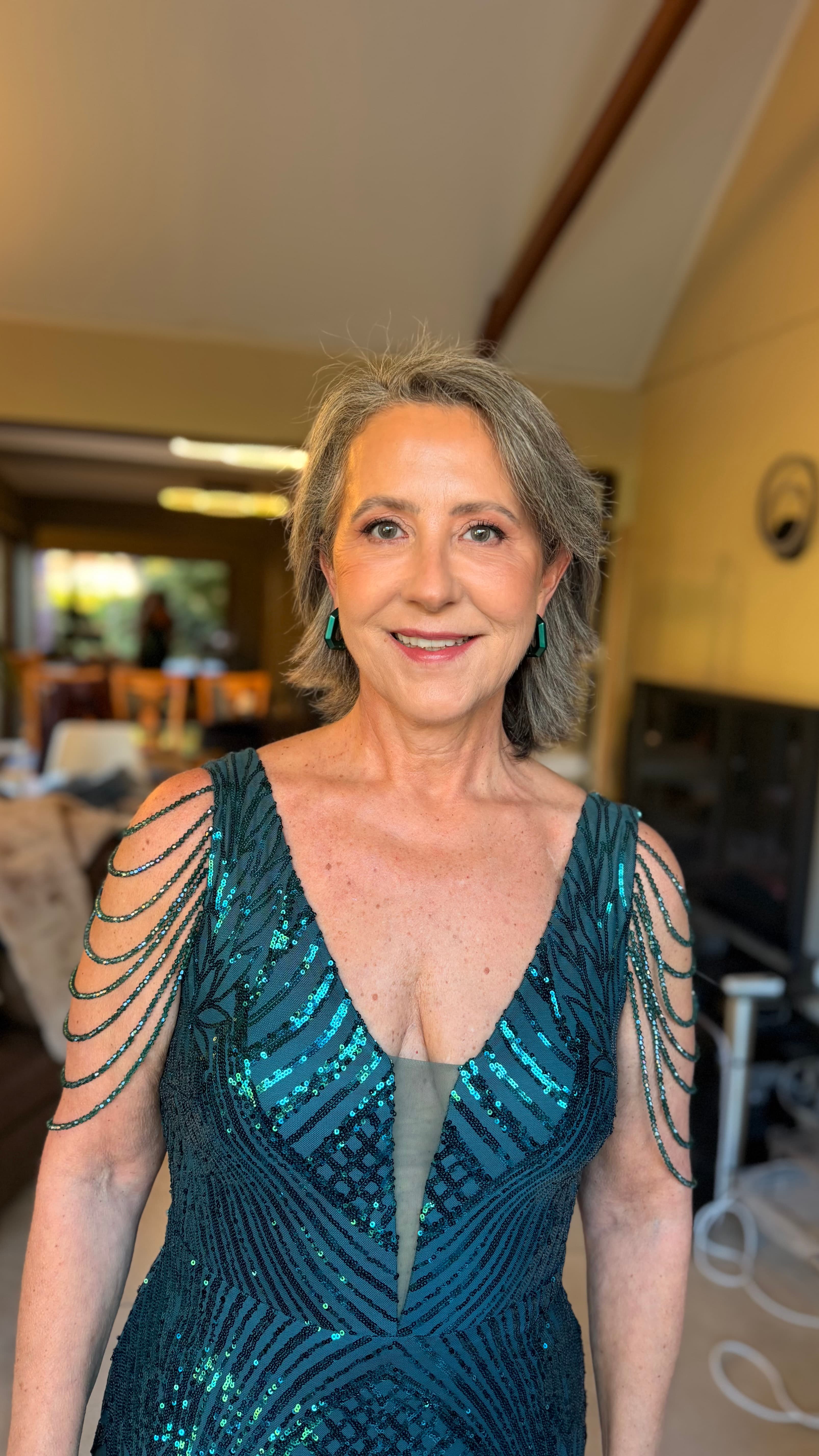 Madrina con vestido azul de lentejuelas, cabello corto y maquillaje de evento
